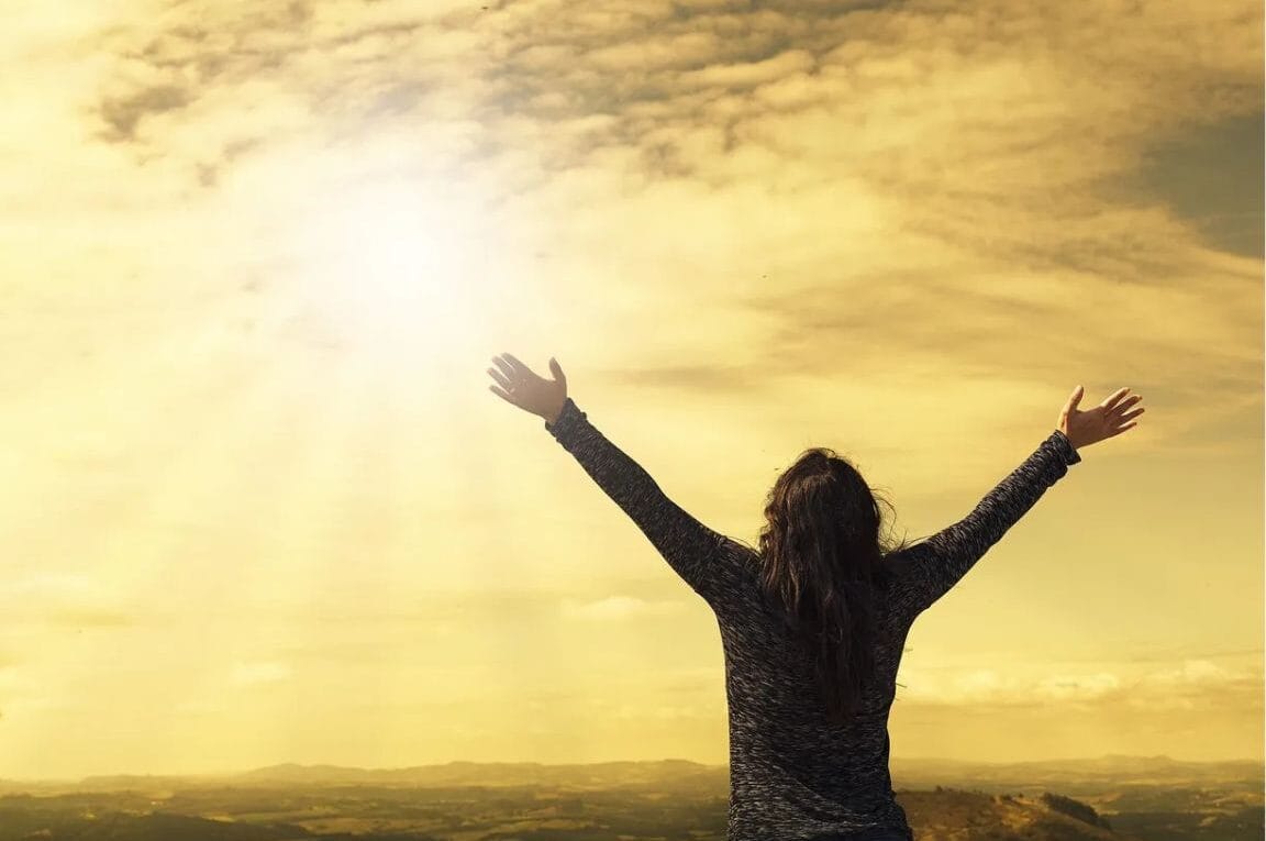 oração da manhã mulher com braços abertos olhando para o céu