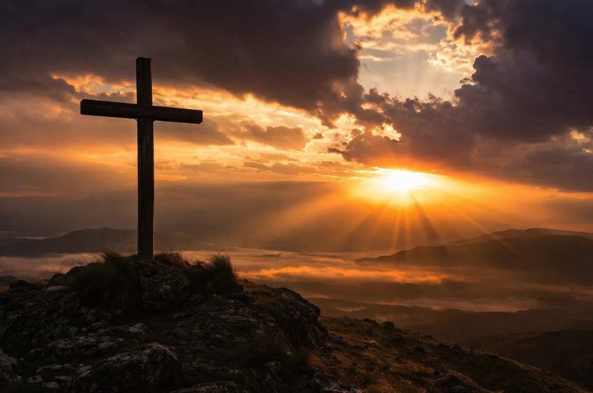 Cruz em um monte e no fundo o sol entre nuvens - Por que Jesus Teve que Morrer